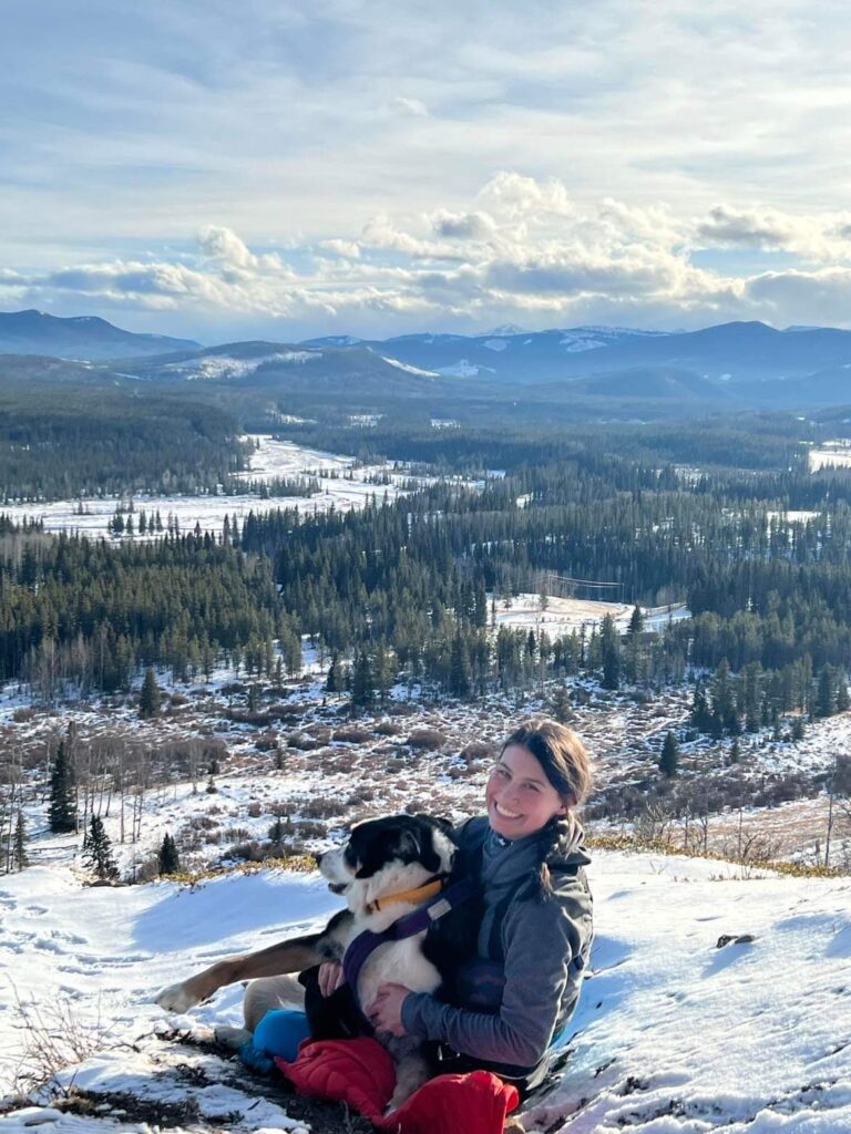 Ali sitting with Guinness Hiking in the mountains